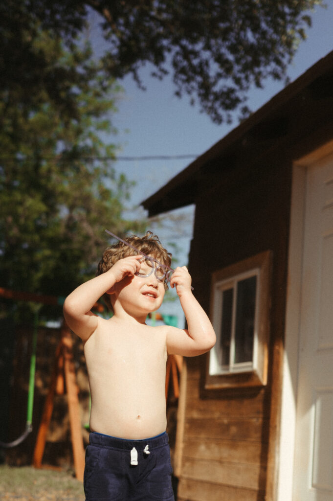 Curly headed toddler boy playing with a crazy straw on a bright sunny day. 