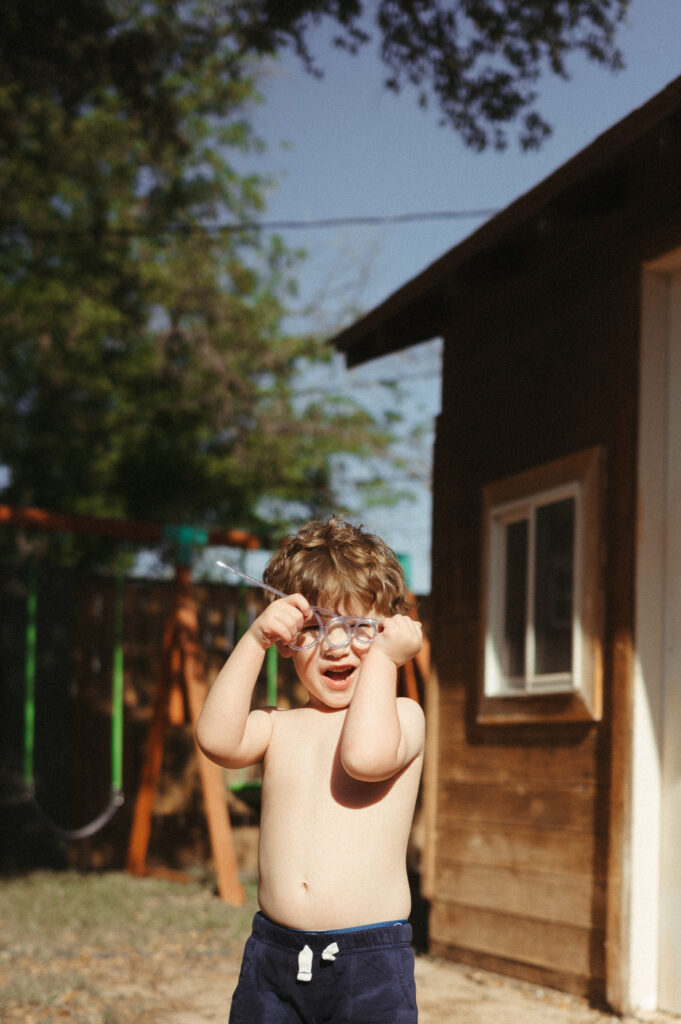 Curly headed boy playing with a crazy straw and making faces.